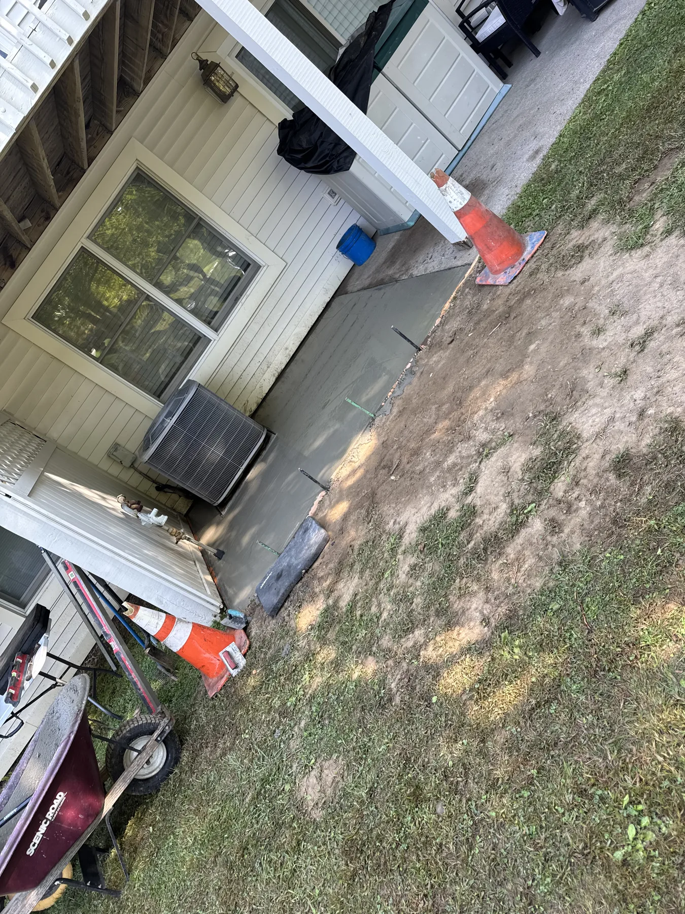 Concrete pad installation in progress beside a home