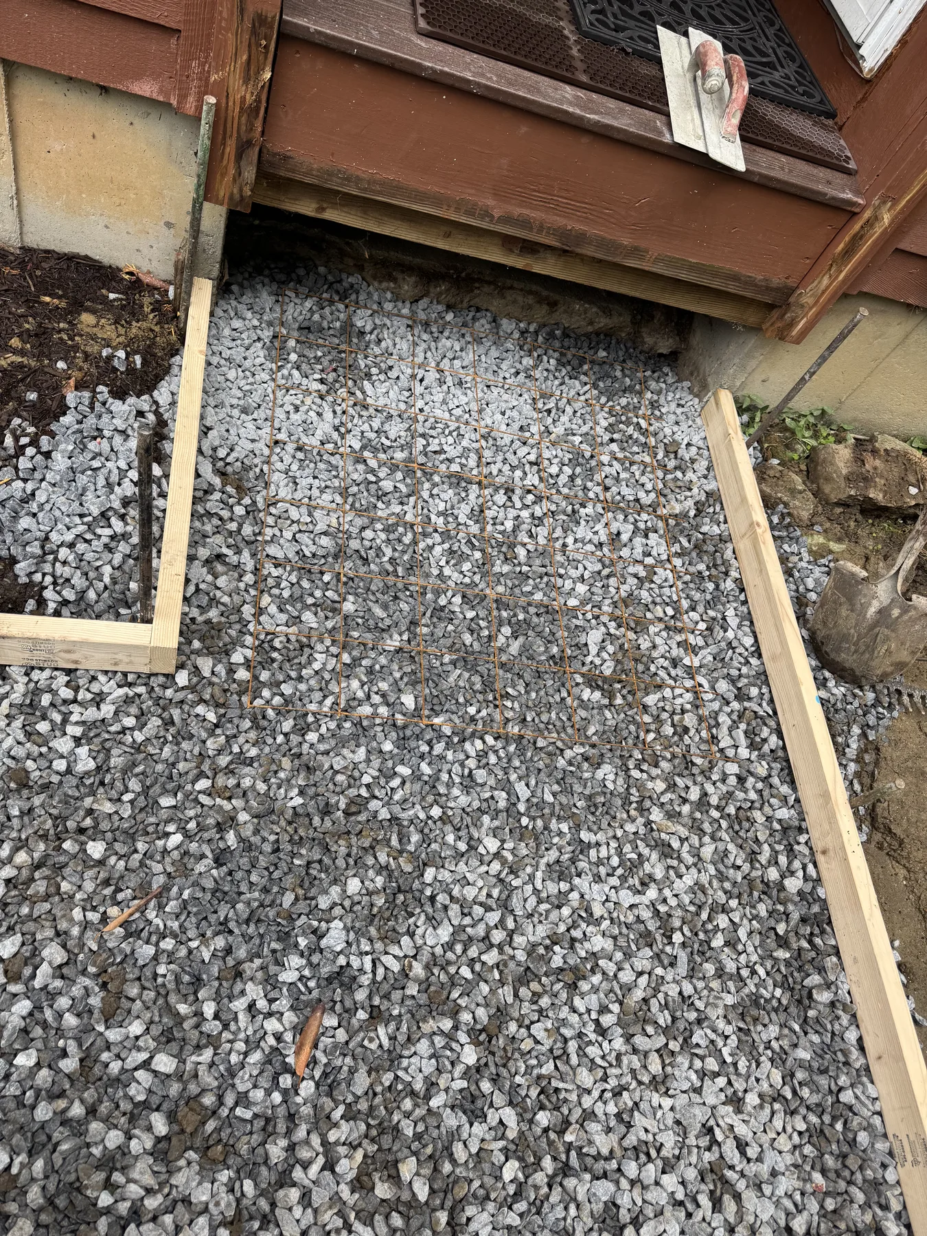 Compacted stone base and reinforcement prepared for a concrete walkway