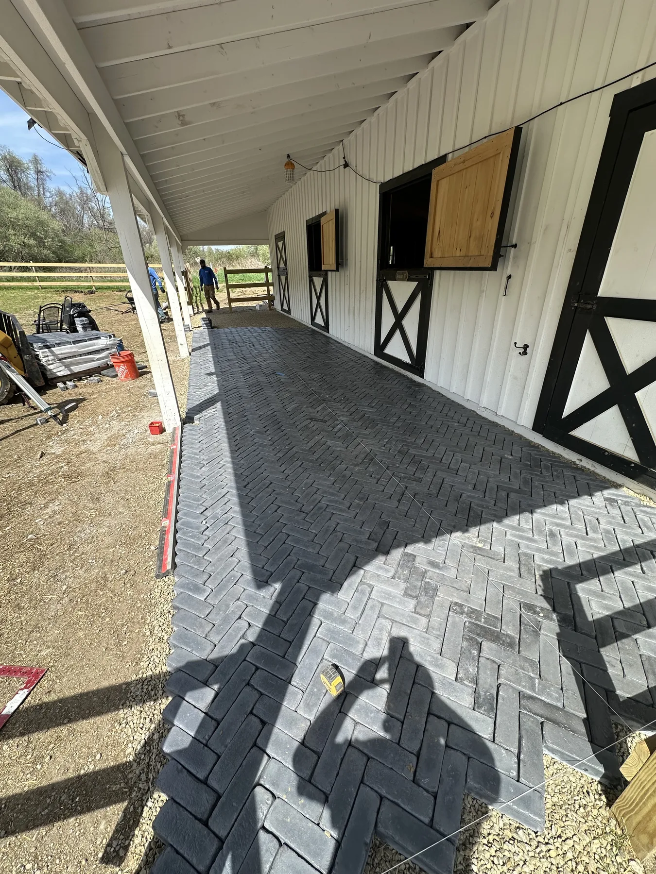 Completed dark paver patio installed beside a commercial barn